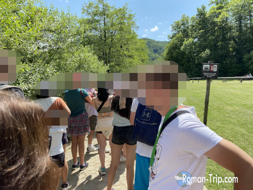 プリトヴィッツェ湖沼国立公園のP3船着き場で、観光客が船を待って並ぶ様子。湖風が心地よく吹き抜ける。/ Tourists lining up at the P3 boat pier in Plitvice Lakes National Park, waiting for the ferry as a gentle lake breeze passes by.