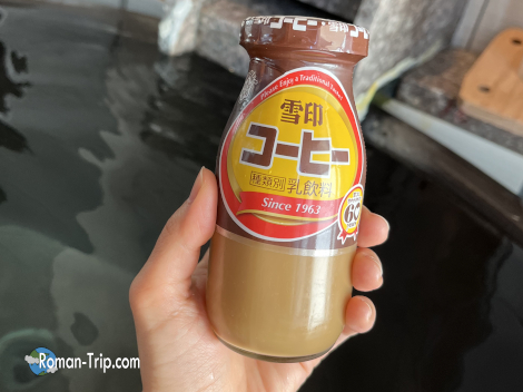 個室露天風呂で楽しむコーヒー牛乳。湯上がりの体に染みわたる、非日常の癒しと贅沢なひととき。/ Enjoying a bottle of coffee milk in a private open-air onsen — the perfect post-bath indulgence in a serene and luxurious setting.