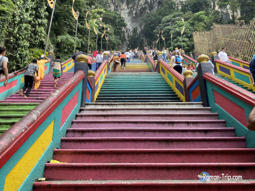 バトゥ洞窟の名物、カラフルな階段。参拝客や観光客が行き交う鮮やかな風景。/ The famous colorful stairs of Batu Caves, a vibrant scene with worshippers and tourists.