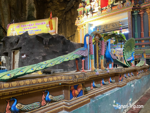 バトゥ洞窟内にあるカラフルな寺院。孔雀が描かれた装飾が目を引く。/ Colorful temple inside Batu Caves featuring decorative artwork of a peacock.
