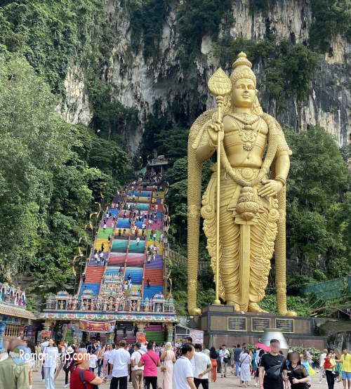 バトゥ洞窟の有名な景色。黄金のムルガン神像（Lord Murugan Statue）と、カラフルな階段、奥に続く洞窟が印象的。/ Famous view of Batu Caves with the golden Lord Murugan Statue, colorful staircase, and the cave entrance in the background.