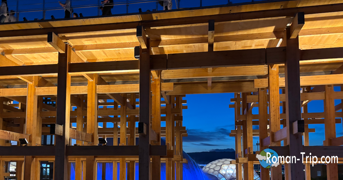 関西万博の夜の大屋根リング。ライトアップされ黄金色に輝く幻想的な光景。/ Night view of the Grand Roof Ring at Expo Osaka, illuminated in golden light creating a magical atmosphere.