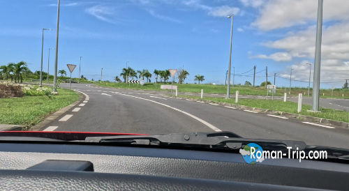 レンタカーでモーリシャスの道路を走行中、ロータリーに差し掛かった瞬間の景色。南国の空と道路が広がる。/ View from driving a rental car in Mauritius, approaching a roundabout under the bright tropical sky.