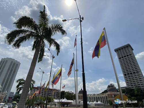 ムルデカ広場に掲げられた巨大なマレーシア国旗(奥)。青空に映える国のシンボル。/ Giant Malaysian flag at Merdeka Square, a national symbol standing tall against the blue sky.