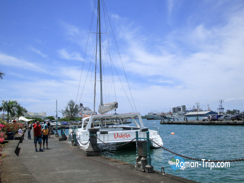 モーリシャスの首都ポートルイスのマリーナに停泊するカタマランヨット。青い海と空が広がる港の風景。/ A catamaran yacht docked at the marina in Port Louis, Mauritius, with the blue sea and sky creating a serene harbor view.