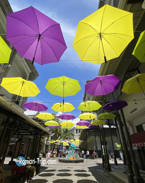モーリシャスのポートルイスにあるアンブレラストリート。色とりどりの傘が頭上を彩るフォトジェニックな通り。/ Umbrella Street in Port Louis, Mauritius — a photogenic walkway decorated with colorful umbrellas hanging above.