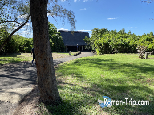 モーリシャスのイル・オ・セルフ行きの船着き場に到着した光景。芝生の奥に船着き場の小屋が見える穏やかな風景。/ Scene at the boat jetty for Île aux Cerfs in Mauritius, with a small dock hut visible beyond the green lawn.