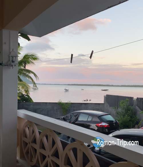 モーリシャスの宿「Apt in La Gaulette」のバルコニーから眺める夕暮れのラグーン。穏やかな海に小舟が浮かび、旅の一日が静かに終わっていく時間。/ Sunset lagoon view from the balcony of Apt in La Gaulette, Mauritius, with small boats drifting on calm water at the end of the day.