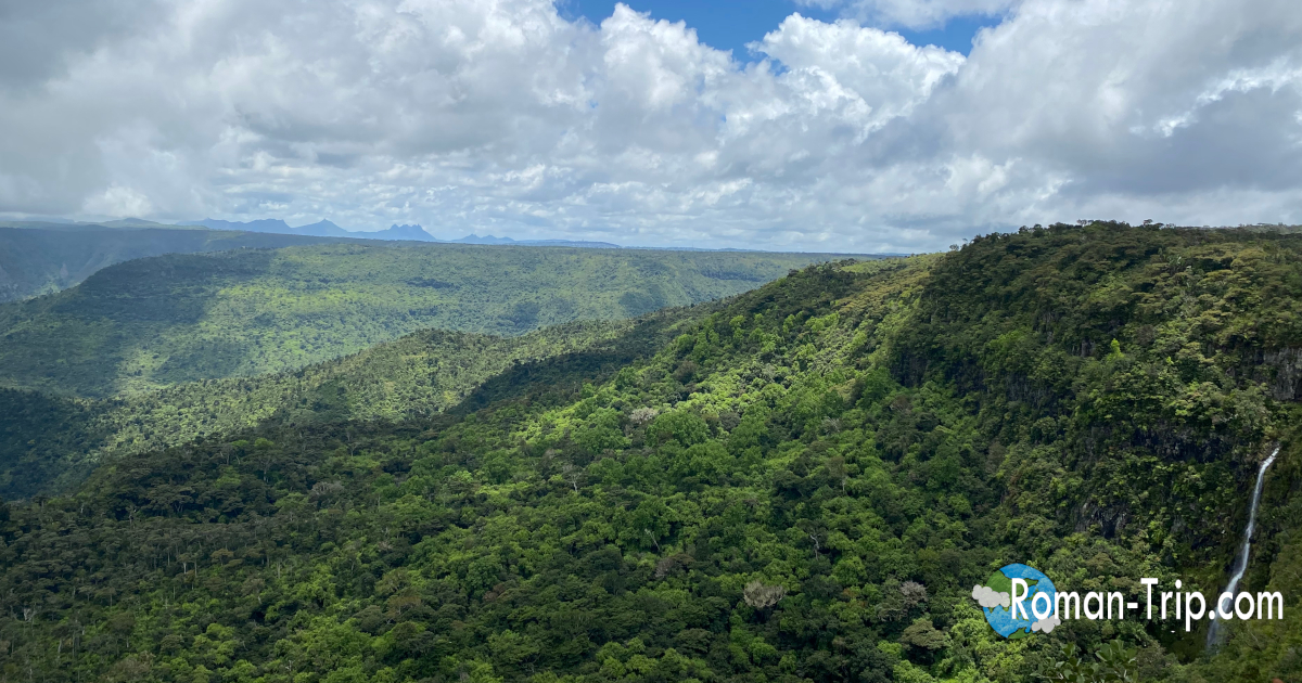 モーリシャスのゴルジュ展望台から見下ろす深い緑の渓谷。雲の影が山肌を流れ、島の内陸に広がる圧倒的なスケールを感じる景色。/ Looking down into the deep green valleys from the Gorges viewpoint in Mauritius, where drifting clouds cast moving shadows across the vast inland landscape.