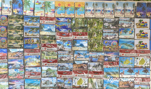 モーリシャスのゴルジュ展望台で売られていたご当地マグネットが壁一面に並ぶ様子。ビーチや山、島の風景など多彩なデザインが旅心をくすぐる。/ A wall filled with Mauritius souvenir magnets at the Gorges viewpoint, showcasing a wide variety of designs featuring beaches, mountains, and island landscapes.