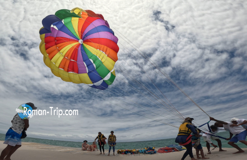 モーリシャスのイル・オ・セルフで体験したパラセイリング。沖合に浮かぶ人工島から、色鮮やかなパラシュートが空へ舞い上がる瞬間。/ Parasailing at Île aux Cerfs, Mauritius — taking off from an offshore artificial island as a colorful parachute rises into the sky.