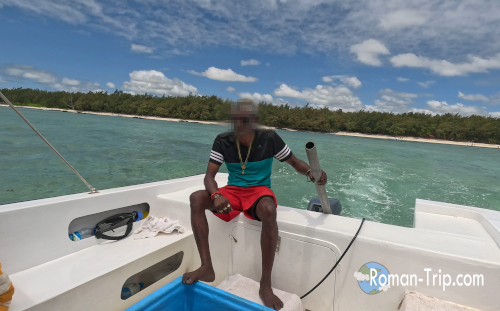 イル・オ・セルフ島でシュノーケリングに向かうボートの後方で、スクリューを操縦するモーリシャスのおじさん。穏やかな海と笑顔に南国らしい空気が漂う。/ A Mauritian boatman steering the propeller while heading to the snorkeling spot at Île aux Cerfs — a relaxed tropical moment on the lagoon.