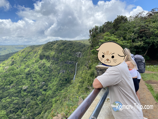 モーリシャスのゴルジュ展望台で滝を望みながら記念撮影。深い渓谷と太古から続く自然を前に立つ、旅のワンシーン。/ A commemorative photo at the Gorges viewpoint in Mauritius, overlooking a deep gorge and waterfall — a travel moment surrounded by timeless nature.