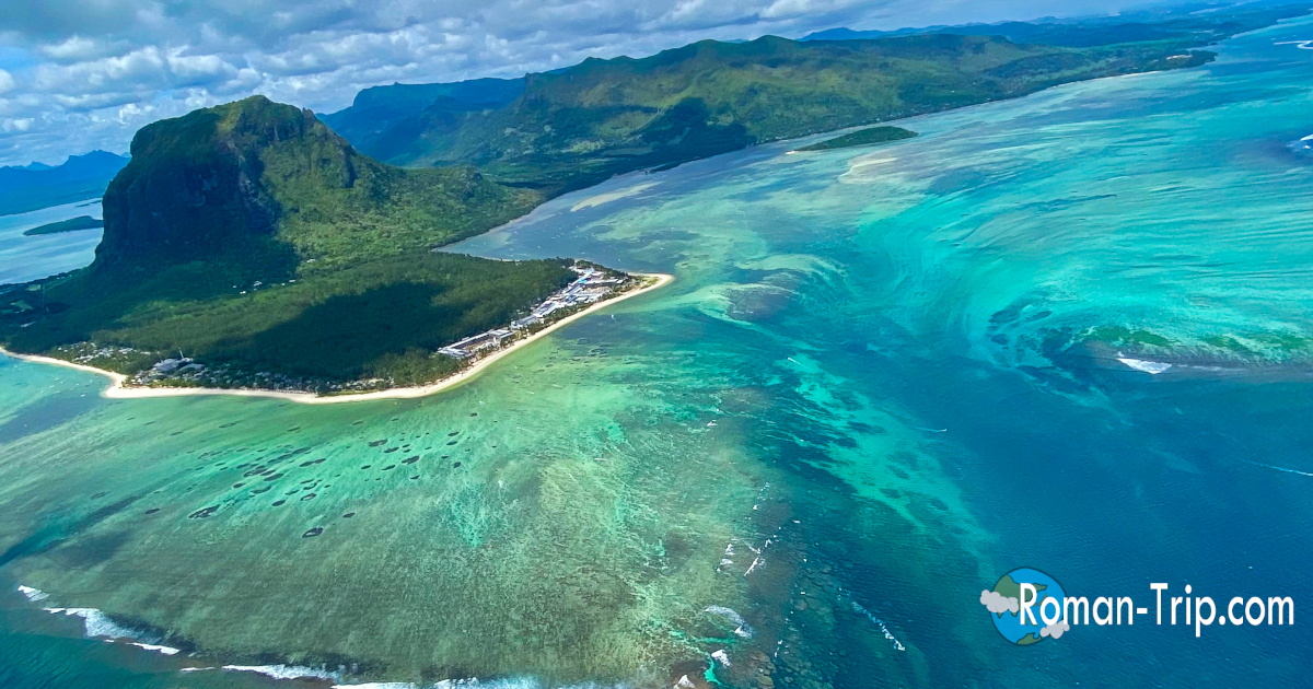 モーリシャスの海の滝を空から捉えた絶景。この旅で一番心を震わせたベストショット。海底の砂が流れ落ちるように見える幻想的な光景が広がる。 / A breathtaking aerial view of the underwater waterfall in Mauritius. The best shot of the trip, capturing the surreal illusion of sand cascading beneath the ocean surface.
