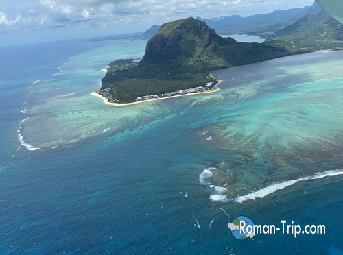 モーリシャスの海の滝がセスナの窓越しに見えてきた瞬間の光景。エメラルドグリーンのラグーンと深いブルーの海が交わり、幻想的な「海の滝」が姿を現す。 / The moment the underwater waterfall of Mauritius comes into view from the seaplane window, where emerald lagoons blend into deep blue ocean, creating the illusion of a cascading waterfall.