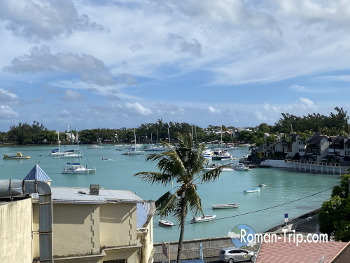 モーリシャスのAzur Paradiseホテル屋上から眺めた海の景色。穏やかなラグーンにボートが浮かび、南国らしいのんびりした風景が広がる。 / View of the Mauritian sea from the rooftop of Azur Paradise Hotel, where small boats float peacefully on the calm lagoon under a tropical sky.