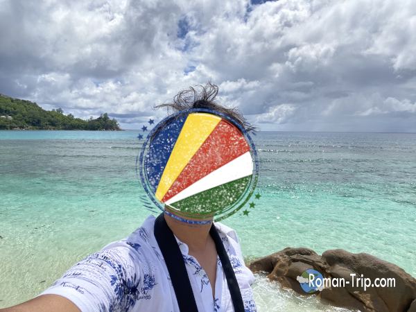 セーシェル・マヘ島のBaie Lazare Public Beachを訪れた記念に撮った自撮り写真。青い海と南国の景色を背景にした旅の一枚。 / A selfie taken to commemorate visiting Baie Lazare Public Beach on Mahé Island in Seychelles, with the tropical ocean scenery in the background.