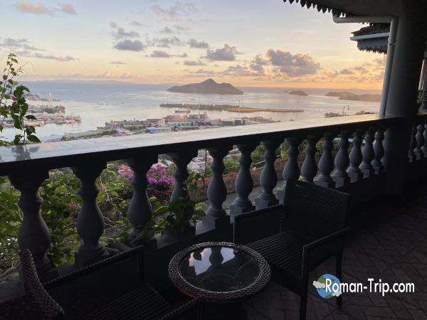 セーシェルの首都ヴィクトリアの中腹にあるホテル「Blue Hill Guest House」からの眺め。港と海、島々を見渡せる絶景の夕焼け風景。 / View from Blue Hill Guest House located on the hillside of Victoria, Seychelles, overlooking the harbor, sea, and surrounding islands at sunset.