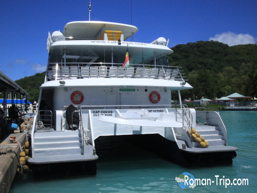 セーシェルのラディーグ島に到着した高速フェリー「Cat Cocos」。島の港に横付けされるフェリーと南国の海の風景。 / The Cat Cocos high-speed ferry arriving at La Digue Island in Seychelles, docked at the island harbor with the tropical sea in the background.