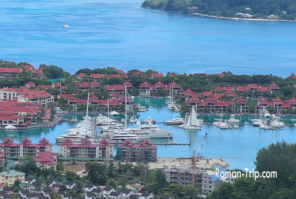 セーシェル・エデン島を望遠で見ると、ヨットハーバーと赤い屋根の高級住宅街が広がっていた。/ A telephoto view of Eden Island in Seychelles, showing the yacht marina and an upscale residential area with red-roofed houses.