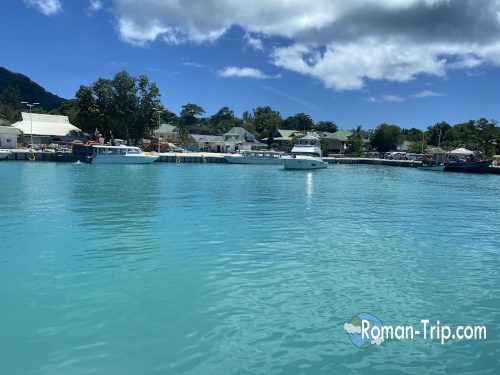セーシェルのラディーグ島に到着したときの海の景色。港の周りにボートが浮かび、透明感のあるエメラルドブルーの海が広がる。 / The sea view upon arriving at La Digue Island in Seychelles, with boats floating near the harbor and clear emerald-blue tropical waters.