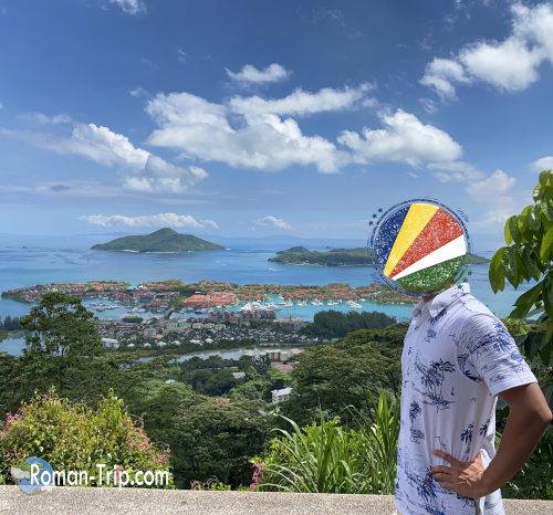 セーシェル・マヘ島のMirador La Misere展望台で撮影した記念写真。背景にはエデン島と青い海の絶景が広がる。/ A commemorative photo taken at Mirador La Misere viewpoint on Mahé Island, Seychelles, with Eden Island and the blue ocean spreading out in the background.